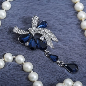Broche nœud vintage avec cristaux bleus et pendentifs en goutte sur fond de fourrure