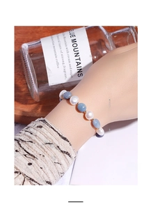 Detail shot of hand wearing a blue aventurine stone and white freshwater pearl beaded bracelet