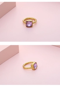 Close-up of a gold titanium ring with a square-cut purple crystal and bezel setting