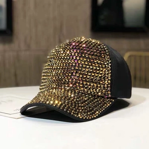 Dettaglio del cappello da baseball nero con densi strass dorati applicati sulla parte anteriore