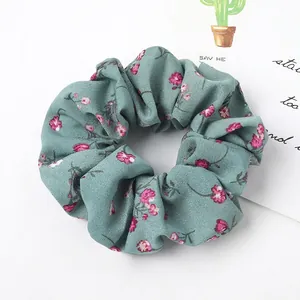 Close-up of green floral scrunchie with pink flower pattern and soft chiffon fabric