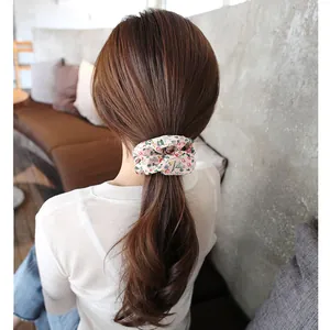 Pink floral scrunchie with colorful flower patterns shown on a low ponytail style
