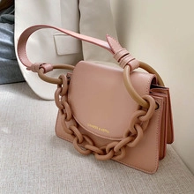 Détail d'un sac à main en cuir rose avec anse à grosse chaîne et finitions dorées