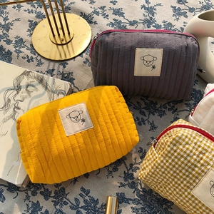 Dettagli di trousse da trucco trapuntate in giallo, grigio e con motivi a scacchi