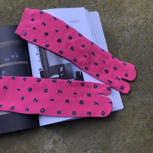 Detail of pink tabi socks with green number pattern on an artistic magazine background