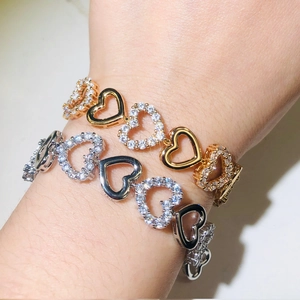 Close-up of gold and silver heart-shaped bracelets with sparkling zircon on a wrist