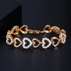 Close-up of gold heart-shaped link bracelet with sparkling zircon pave on black background
