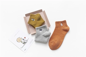 Close-up of three pairs of cotton socks featuring cute animal embroidery in warm colors