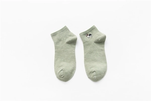 Detail of light green cotton socks with ribbed cuffs and cute dog embroidery on white background