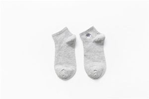 Detail of grey cotton socks featuring a small cute cartoon animal embroidery on the cuff