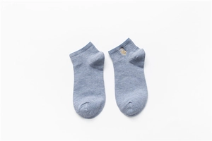 Detail of blue cotton socks featuring a cute owl embroidery on a clean white background
