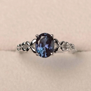 Elegante anillo vintage con gema azul ovalada, motivos de hojas y banda de plata