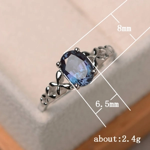 Anillo de compromiso con piedra ovalada azul púrpura y detalles de flores