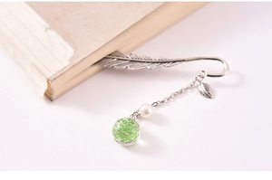 Macro detail of silver feather metal bookmark with pearl and dried flower glass ball