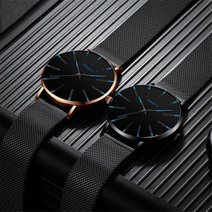 Detalle de relojes de cuarzo en oro rosa y negro con correas de malla sobre metal