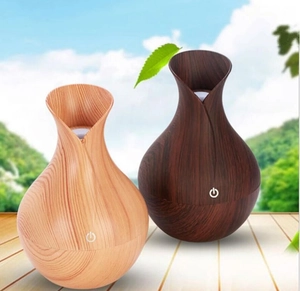 Vase-shaped wood grain humidifiers in light and dark finishes on an outdoor terrace