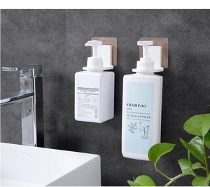 Detail of wall-mounted shampoo bottle holder with transparent adhesive on grey tile wall