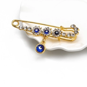 Macro view of gold angel wing pin with crystal embellishments and blue evil eye charms