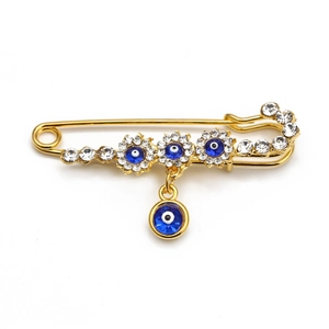 Detail of gold angel wing brooch with blue evil eye flowers and sparkling rhinestones