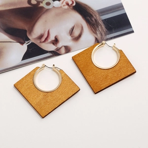 Detailed close-up of square wooden earrings with embedded polished gold metal rings