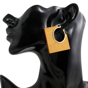 Geometric wooden square earrings with golden metal hoops shown on a black model