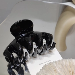 Close-up of a glossy black hair claw clip with a modern minimalist design and mirror finish