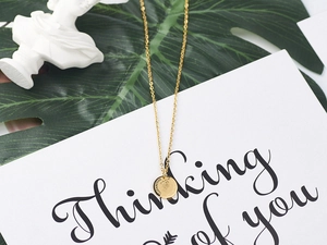 Macro detail of golden Queen Elizabeth II coin pendant necklace on a minimalist card