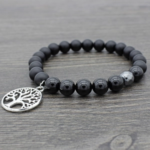 Black agate and obsidian mala bead bracelet with a silver Tree of Life charm on wood