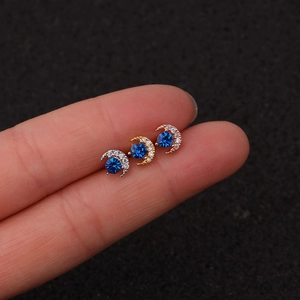 Detailed macro view of moon-shaped earrings with blue center zircon on fingertips