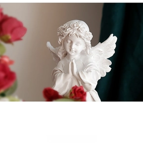Macro detail of a white resin praying angel statue with floral wreath and wings