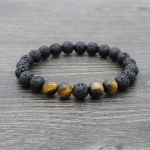 Lava stone and tiger eye yoga beaded bracelet on grey wood surface, main view
