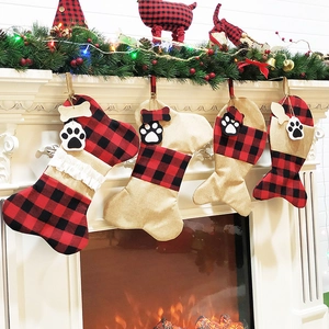 Set of 4 buffalo plaid and burlap Christmas stockings in bone and fish shapes by a fireplace