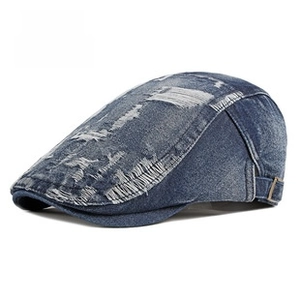 Close-up of vintage blue denim flat cap featuring heavy distressed ripped details and texture