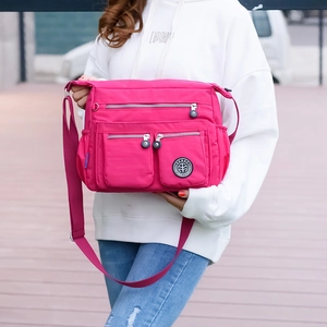 Detail of fuchsia waterproof nylon shoulder bag with multi-pocket design and adjustable strap