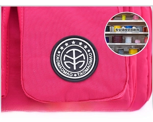 Detail of the black rubber logo badge on durable rose red nylon waterproof shoulder bag