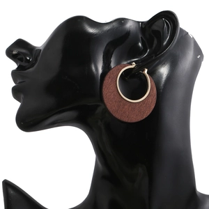 Dettaglio dell'orecchino a cerchio in legno marrone con anello d'oro su modello nero