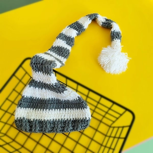 Detail view of handmade grey and white striped long tail knit baby hat with soft white pompom