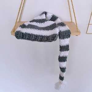 Detail of grey and white striped knit baby hat with long tail and fluffy yarn texture