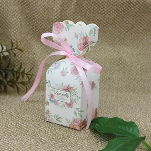 Close-up of a floral paper gift box with pink ribbon on a natural burlap background