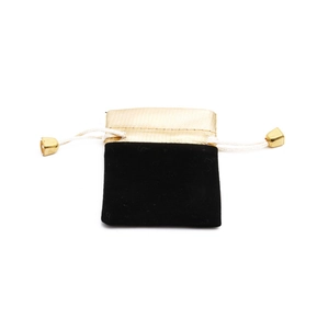 Macro detail of black velvet jewelry pouch with golden fabric and metallic drawstring