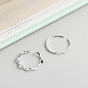 Close-up of twisted rope and textured minimalist S925 silver rings on grey background