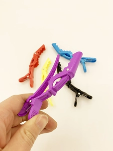 Close-up of a professional purple hair crocodile clip being held for salon hair styling