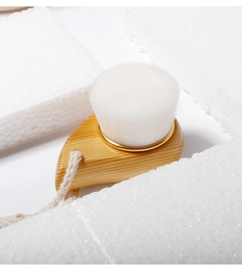 Close-up of wooden facial cleansing brush with soft white bristles and beige hemp rope