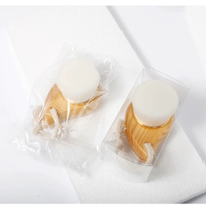 Detail of bamboo facial brushes with soft white bristles in bag and box packaging