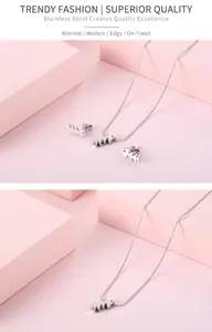 Makroaufnahme von minimalistischem Fischgräten-Schmuckset aus Edelstahl auf rosa Blöcken