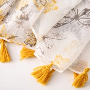 Close-up of lightweight linen scarf with yellow butterfly prints and fringe trim