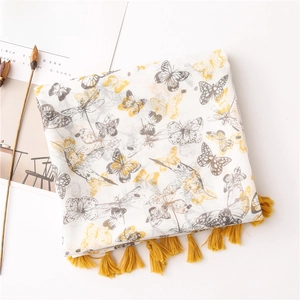 Detailed close-up of ivory butterfly print scarf with bright yellow fringe tassels
