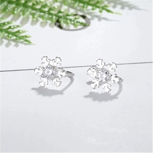 Macro detail of snowflake-shaped silver earrings featuring a central sparkling zircon stone