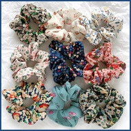 Flat lay of nine assorted floral fabric scrunchies in various colors and patterns