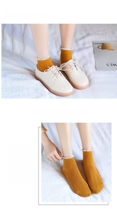 Detail showing ginger yellow cotton socks with white lace edge and vertical knit texture